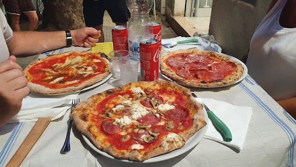 Tre pizze appena servite su un tavolo apparecchiato
